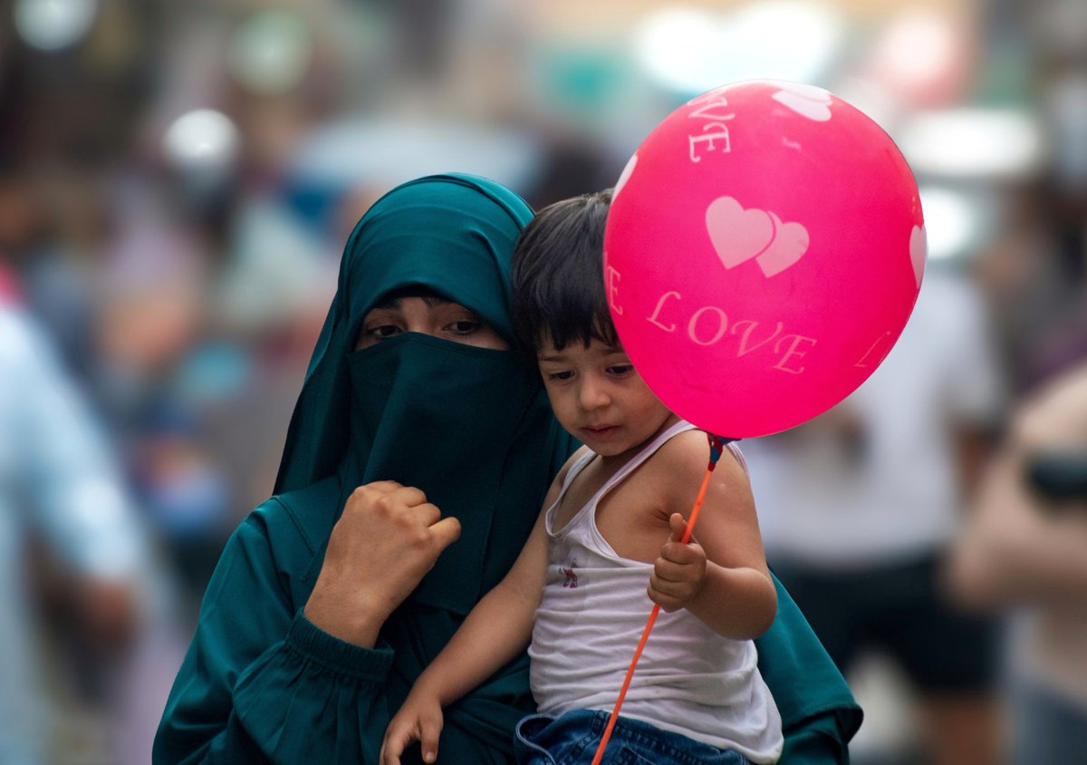 faisalbashirs's tweet image. A #Kashmiri hijab-clad #woman carries a #child as she walks through a #market during a #hot #summer day in #Srinagar on #August 1, 2025. Photo by @faisalbashirs