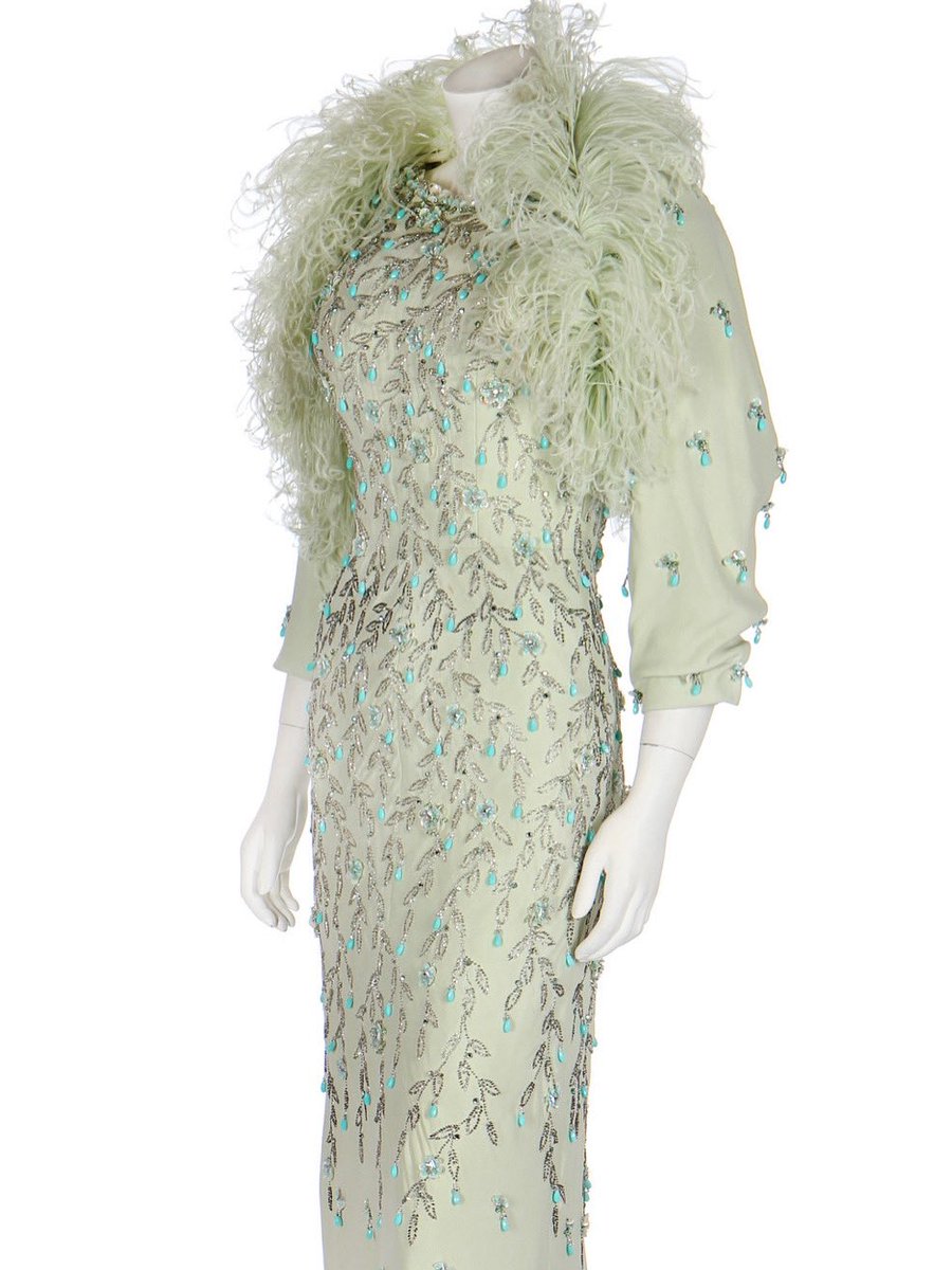 Sea foam green laps around the throat, thanks to the feather trimmed bolero that sits over its matching dress. The crepe dress is encrusted with iridescence with glass beads and sequins all Sea foam green laps around the throat, thanks to the feather trimmed bolero that sits over its matching dress. The crepe dress is encrusted with iridescence with glass beads and sequins all