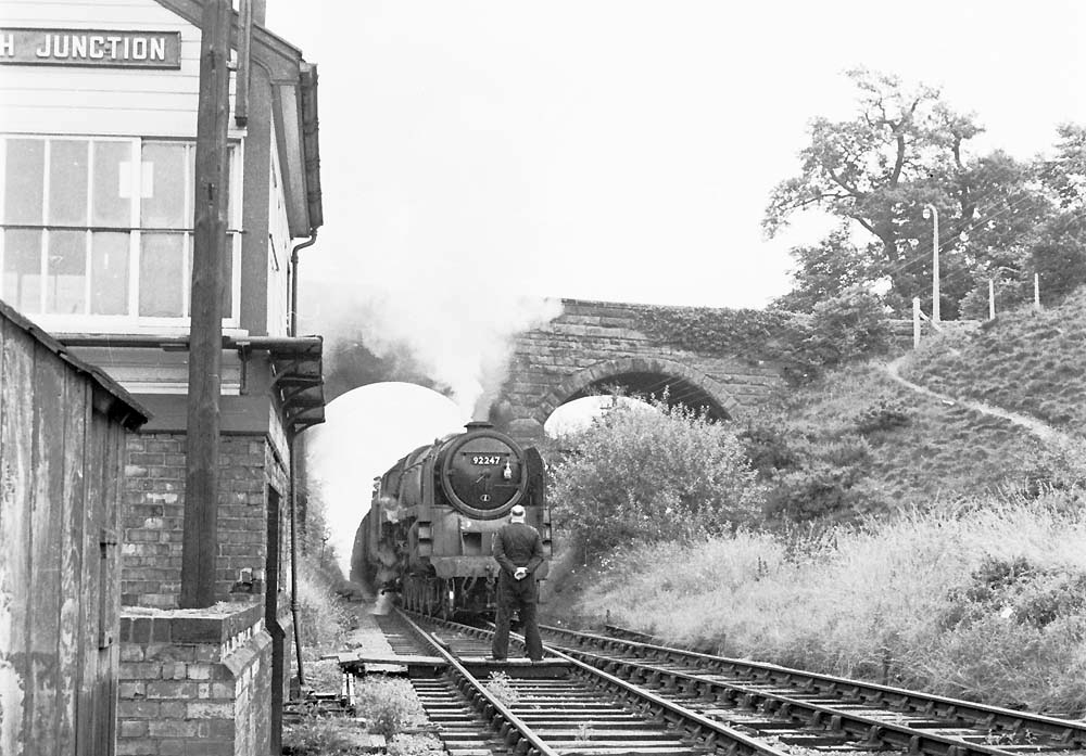 Kenilworth Junction, July 1965

British Railways Standard Class 9F 2-10-0 No 92247 approaches Frank Prew the signalman who waits to take the staff from the Leamington bound train.

Photo by R Hickman and information by Barry Hickman