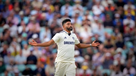 The image shows Mohammed Siraj, an Indian cricketer, on a cricket field, wearing a white uniform with "DREAM11" on the jersey, gesturing with arms outstretched. The setting is a packed stadium with a blurred crowd in the background, indicating a lively match atmosphere. The post text highlights Siraj\'s performance in a recent Test series, noting his 23 wickets in 5 matches as the top wicket-taker, emphasizing his significant contribution in a batting-friendly series. No platform watermarks are visible.