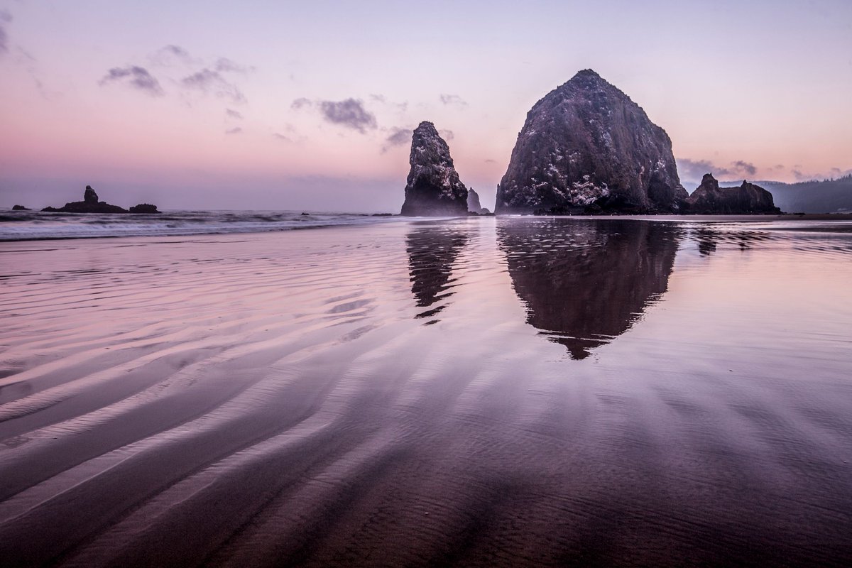 An early morning pink glow encompasses Haystack Rock at Cannon Beach in Oregon. #landscapephotography #artforsale #cannonbeach #oregon #picoftheday  Click link for pricing and purchase: Please refer to link for info and pricing buff.ly/4fiRgPd
