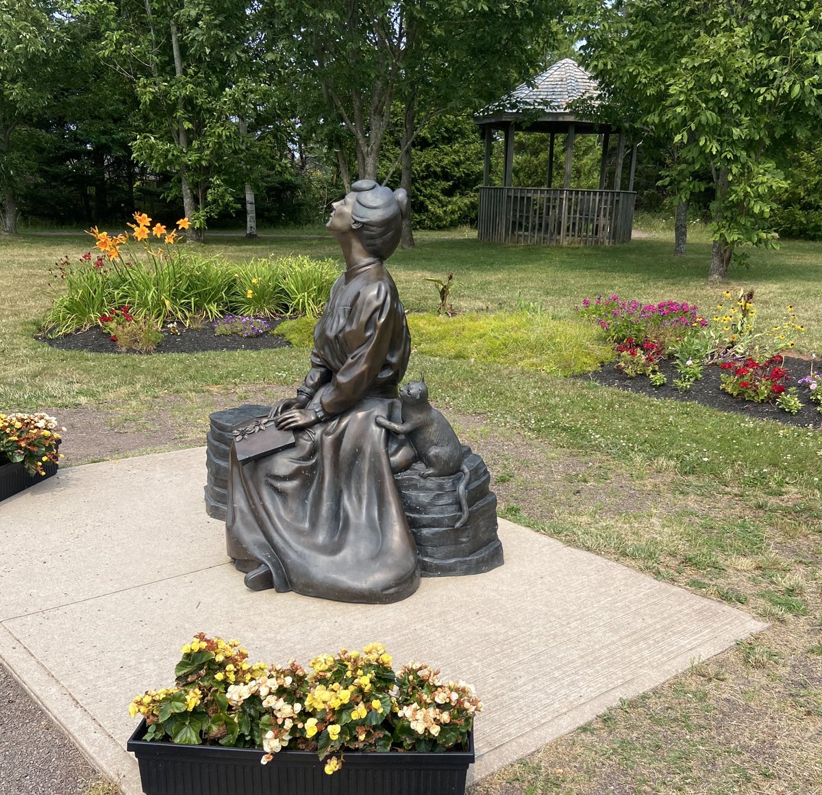 Behind many great women …. is a cat pestering her to be fed 🐈

Pictured: Statue of L.M. Montgomery, author of Anne of Green Gables.