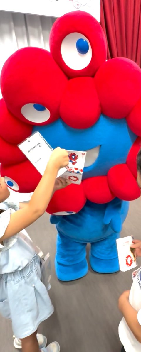 ミャクミャクに自慢のスタンプパスポートを見てもらうために、なぜかミャクミャクの口にパスポートを向ける娘
