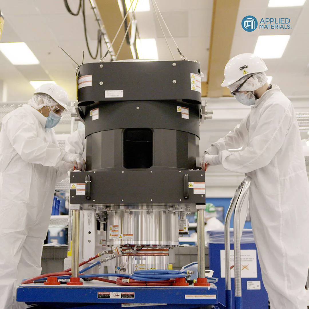 Two technicians in cleanroom suits working on a machine at Applied Materials.
