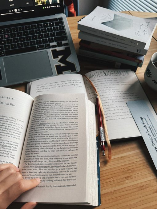 whirlwind of words and ideas swirling on a desk, bathed in the soft glow of laptop light📚💻✨