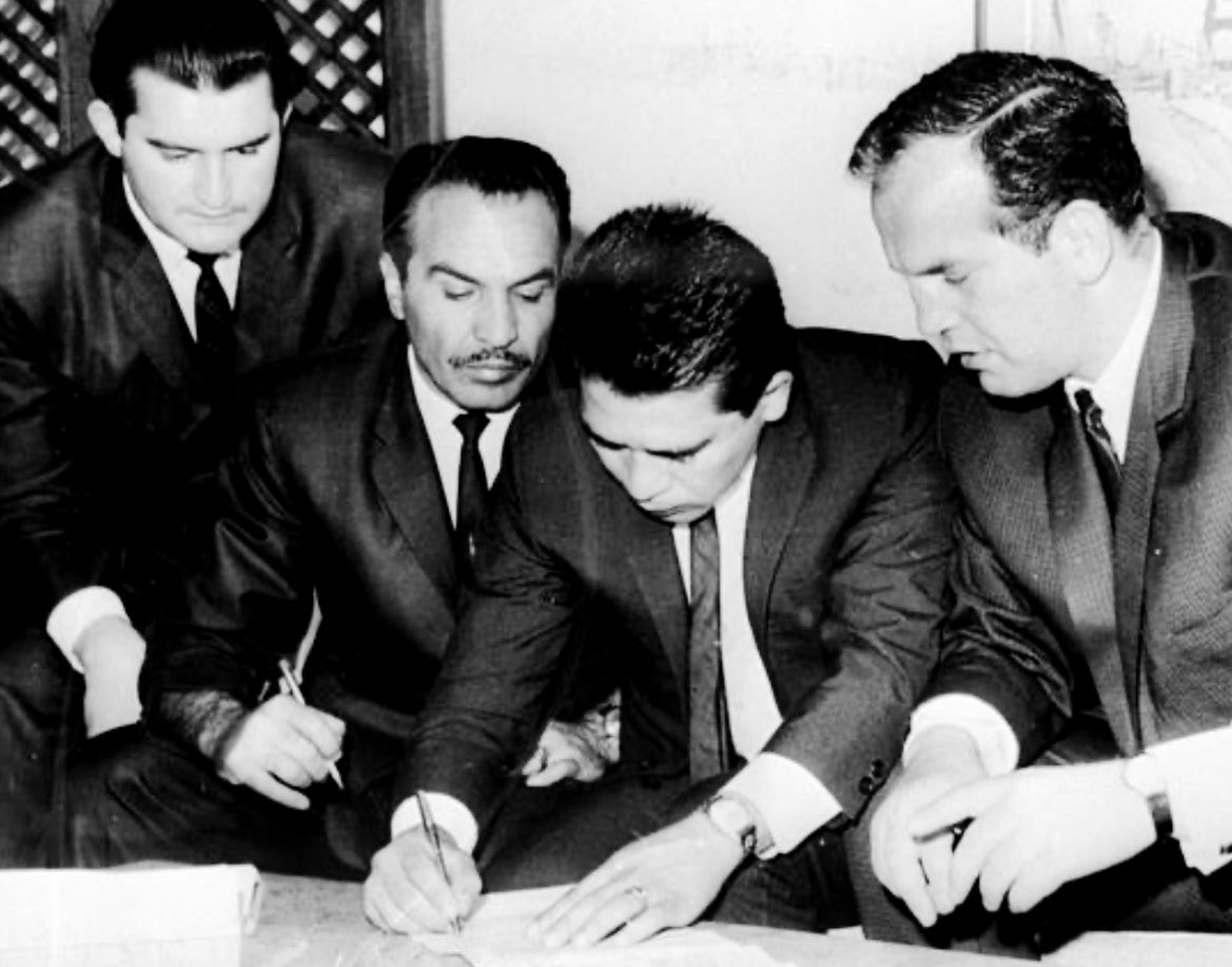 Mickey Duff looks on as the great Vincente Saldivar signs a contract to take on Welshman Howard Winstone at London’s Earls Court in September 1965.