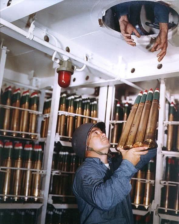 A crewmember aboard USS Alaska (CB-1) passing  40mm ammumition out of the of the 40mm handling rooms aboard the cruiser. A hatch in the overhead allows him to hand off the ammunition to the next sailor. The photo was taken on 6 March 1945 while operating off of Iwo Jima.

The