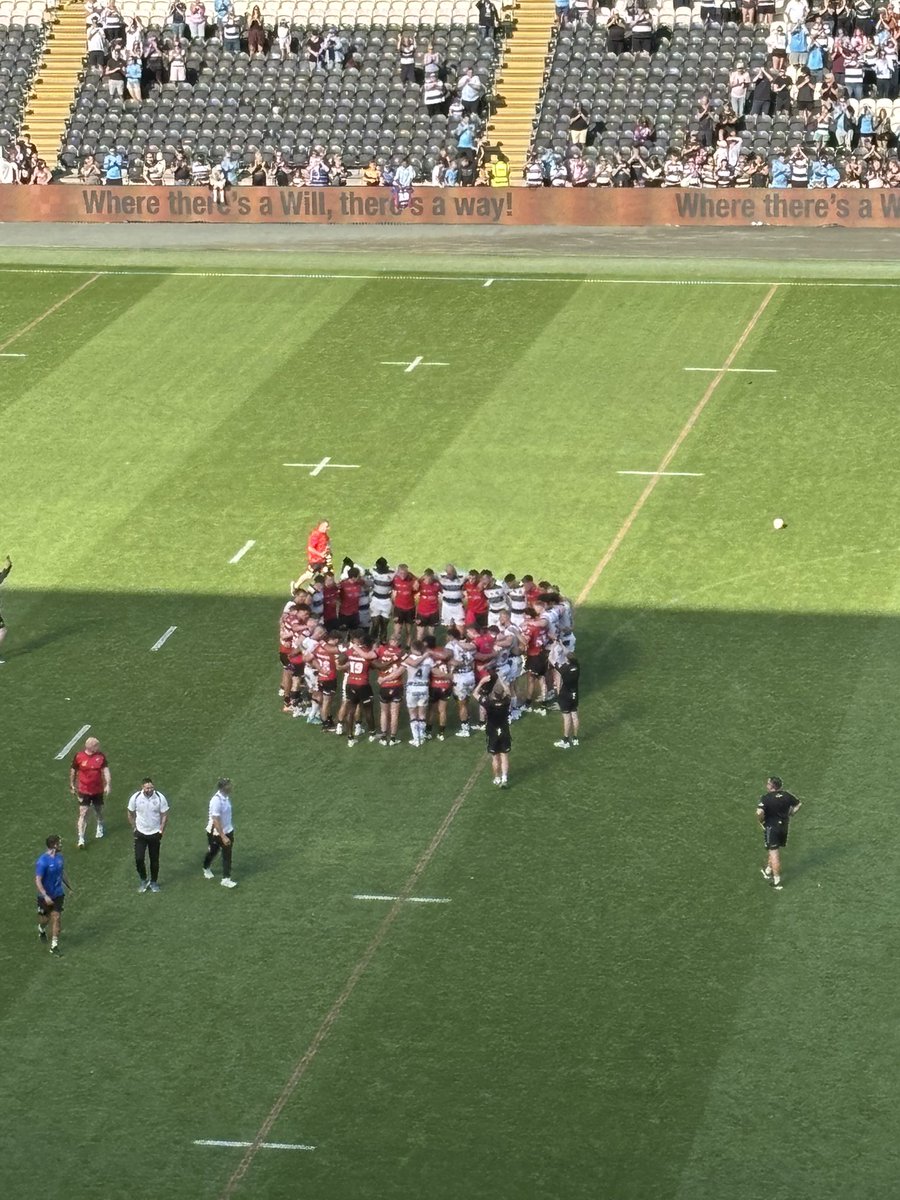 Hull FC and Salford Red Devils player gather together on the field. A moment of unity and support for the Salford cause