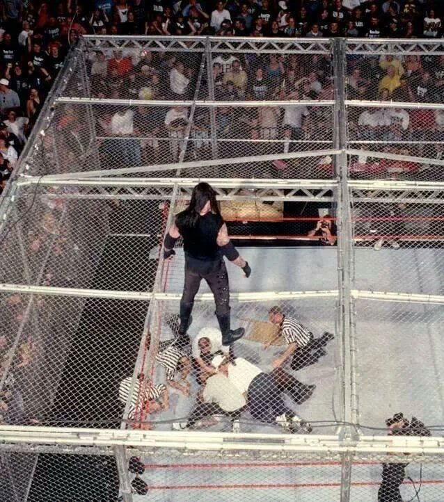 The Undertaker looks down at medical staff checking on Mankind after he fell, unscripted, through the top of Hell in a Cell into the ring 16ft below in 1998