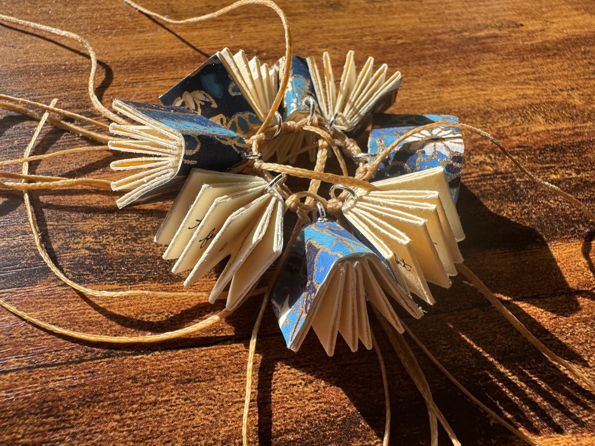 meiageddes's tweet photo. This ring of eight miniature books and thread make up a poem that can be read in any number of ways. It’s a circular blue sky-sea creature  that wants to feather its way to freedom. On display with the Building Books 3 Exhibition at the Mark Twain Library until 9/2/25 📚 https://t.co/woqw2tD7Pf