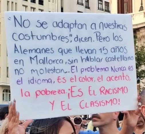 Qui porta la pancarta Déu sap els anys que viu a Mallorca... sense parlar català, que és la llengua pròpia de Mallorca. El problema, per als espanyols, és la llengua: el "color" de la llengua, l'accent. És "racisme" lingüístic, classisme, colonialisme. Inadaptats.