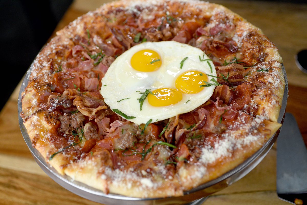 Dig into The Carnivore! Our house red sauce, mozzarella cheese, pepperoni, sausage, bacon &amp; black forest ham pizza topped with a sunny side up egg &amp; fresh basil is adored by all! 🍕🥓🥚 #GrindstoneTapHouse #FoodieFavourite #PizzaLovers
