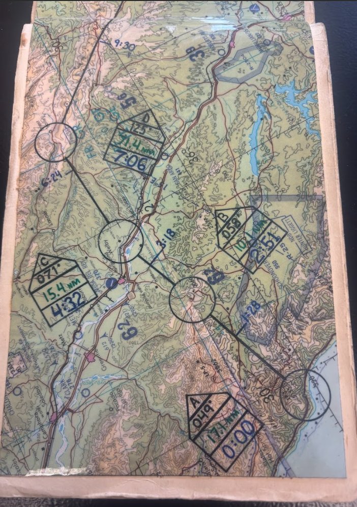 RSE_VB's tweet photo. #TomcatTails Number 36
#TomcatTuesday

“On time, on target means exactly what it says.”

Time means many different things to people. Some folks are fairly loose with their definition of “on time”, others are more focused on it. In the military there’s an old adage that “if you’re 5 minutes early, you’re 10 minutes late.” And within the military, particularly among the more tactical operators, the words “on time” have a very specific meaning. They mean “ON TIME”. If a specific action is supposed to occur at, say, 12:00pm, then that means 12:00:00. Not 12:03. Not 11:56. Not even 12:00:32. It means 12:00:00. Period Dot.

This is no more true than when performing the air-to-ground mission whether a pre-planned strike or a close air support (CAS) mission. If the warhead needs to go through the window of a building and fuse at 12:00pm, the you design the entire strike to have that happen on the second, to include hitting various waypoints on the strike route to the second, releasing the weapon on the second, and even factoring in the time of fall of the weapon, which can range from a minute or more for longer range bombs or 15-17 seconds for a free falling gravity bomb. The reason for this is simple. In these scenarios, there are often follow on activities planned after the weapon fuses so being sloppy on timing can delay that activity or get people killed. So yes, the military takes “time” very seriously.

Modern aircraft have highly accurate navigation and time keeping systems so it’s much easier to be accurate to those tolerances than it used to be.  In the way-back days of flying the F-14A “Bombcat”, the INS (Inertial Navigation System) was really just a suggestion of where you were in the world, and the only clock you had was the 8-Day analogue timepiece on the instrument panel or the $42 G-Shock on your wrist. Such it was when we competed in the annual “Bombing Derby” in the VF-24 Renegades when I was stationed at Miramar.

The Bombing Derby was kind of fun and also a bit new for us former air-to-air only Fighter Guys. Since my Dad was an old “air-to-mud” pilot (A-1, A-4, A-7) I had an affinity for that mission because watching stuff go BOOM on the ground was very cool. All the Miramar squadrons participated in the Derby and wanted to win bragging rights for the best scores. As I recall, each squadron was scheduled for 4 flights of 4 singles with TOTs (Times on Target) spread over an hour, every 15 minutes (or something like that).

On that day, the Weapons School nerds would come over and brief your flight on your scenario, your target, and your individual TOT. They couched it in some threat scenario of hostile country X with air defenses Y and target Z that needed to be taken out at exactly time XX:XX that day. In reality it was going to be a low level route around the Salton Sea terminating at the Loom Lobby bombing target just north of Plaster City, CA near El Centro.  The nerds would do a time hack so you were synched with their watch and depart so you could do your flight planning. They took off for El Centro to eventually drive to the scoring tower near the target area to grade each jet.

Time hack? What the hell is that, Corky? Well, back then you couldn’t get exact time off the interwebs (didn’t really have access to that) or your cell phone (didn’t have those either). So you had to call a phone number (853-1212??) and a voice would say “at the tone, the time will be…1021…and 50 seconds” or whatever. You would then adjust and set your digital watch (yes, we had THOSE) to that exact time. During the brief you’d always start it with a time hack at the brief time. You’d call the brief to order with something like “20 seconds until time one-zero (1000). 10 seconds until time one-zero. Five, four, three, two, one, MARK, time one-zero”. This served two purposes; everyone was now working off the exact same time AND you started your brief on the hack exactly on time. Overkill? No. There is precision, and there is everything else. Better stated: how you do anything is how you do everything.

On our assigned day, we got the morning brief for a low-level route that ran counterclockwise around the Salton Sea (1256? 1266? Anyone??) and our assigned target and TOTs. For clarity, let’s just say mine was 12:00pm. Now we had to start briefing the flight where each Tomcat would launch out at the appropriate time to transit to the starting point of the low level (Point Alpha), form a holding stack nearby, and then sequence out to Point Alpha at the right time to end up at the target on time. Lot’s of precision planning, along with lots of Zen in the actual execution which you’ll see at the end.

Of note, when running a low level back then we had no NAV system that was reliable enough to hit each of the designated points. We had to spend time making what were called Strip Charts, pictured above. Yes, this was a manually developed, hand cranked navigation aid you literally held in your hand and looked at while you modulated your speed, checked your watch, compared actual to desired time at each point, and then adjusted speed faster or slower to re-check it all at the next NAV point. We literally WERE John Wayne back then with analogue tools and Kentucky windage on our side but nothing else. Also, when you’re raging around on the deck you may eyeball the wrong spot on the ground and think you’re right on route but were actually nowhere near it. Ask my friend “Baja” how that works!

And you can see on the photos above the NAV points, the route, and the little “dog houses” at each that contains (at Point A):
Point ID – Alpha
Heading to next point – 049°
Distance to next point – 17.1nm
Time at Point Alpha – 0:00 (start of route where you actually start your timer on your watch)

And on and on for all the rest of the points culminating in the last point before the target.

We all launched with our Mark 76 blue practice bombs (25-pound bombs we called “Smurfs”) and headed for the holding point. We’d all made it on time and were in position to start so Dash 1 then Dash 2 pushed on the route and I waited for my turn. We’re circling down low at around 1,000 feet and I’m playing my holding turn so that I can hit Point Alpha at exactly 500 feet, exactly 360 knots, and at the right time of day to get to the target as close to 12:00 as I could. We used speeds in multiples of 60 because the math was easier (360 = 6 miles/minute, 420 = 7 miles/minute, or my favorite 600 = 10 miles/minute). For the sake of this story, let’s say the route took 45 minutes, so I wanted to cross RIGHT over Point Alpha at 11:15:00 to give me the best chance.

Sure enough we hit it right as planned and I hacked my stopwatch, and off we went. Most guys will tell you that some of the best flying is doing low level routes because you get that ground rush, you get to see all kinds of cool stuff up close, or get to thump (pass low over) things like trains and ranger stations. And some of the BEST low-level routes are over the desert because you have mountains and terrain to fly around. While it’s not quite like the low level scene in Topgun; Maverick, it IS vaguely similar in the opportunity to fly thorough valleys and over mountains and knife-edge peaks. Truly beautiful scenery passing by at 6 miles a minute!

Also fun is hitting your turn points and pulling a hard turn left or right just over the ground, zorching around down low with that immediate visual feedback. As we flew along the route we would get off time here and there as is expected and had to make corrections. I’m pretty sure there’s a formula for things like “15 seconds behind at 360; for how long do I have to go how fast to catch up?” My RIO could probably figure that out, but up front my plan was just “go faster for a bit.” And it seemed to work pretty well for each correction; that’s partially where the Zen comes in.

My favorite part of that route is when we’re northwest of Salton Sea and headed to a hard left turn point that is centered right on a Ranger Fire Observation Station at the top of the northern end of a knife edge peak (or close enough to it for fun). As you approach it at 500 feet and the speed of heat, this beautiful peak extends up a thousand feet out of the desert floor impossibly steep, with the north end on your nose and the rest extending to your left. At 5 miles away you can pick up your nose and climb to meet that northern end where the turn point is (ish). And then you can see the Ranger tower that looks like a big log cabin on stilts sticking above the edge of the peak and start to angle just a hair to the right of it, planning on your left turn toward the south and the target area. Just before it flashes past your left wing, roll 90° angle of bank left and pull HARD, showing the Ranger a full planform Tomcat seemingly close enough to reach out and touch. Often you would see the Ranger at the rail, looking right at you and waving his arms in the air. F*cking epic. It’s little things like this that keep us in the cockpit.

We course corrected back to the route, checked our time and pressed on toward Loom Lobby. The last turn point on that route is right near Ocotillo Wells with a little airport, so heads out looking for the random bug smasher (light civil) and once clear it’s hard right 160° to hit the run in line for the target. At this point you’d better be close on timing as you really can only correct a few seconds here and there now. We hit that last point a little ahead of time (15-20 seconds maybe?) so I’d need to Zen/John Wayne a little correction somewhere.

My RIO read in air-to-ground on the system, double checked his AWG-15 panel over his left knee and we were good to go. I switched A/G on the HUD and had good symbology (thank you, God) and lined up for the run in. We’d planned a 45° dive out of the “pop up maneuver” for better accuracy and when we got to the right point on the ground about 3.5 miles from the target, I initiated the maneuver. Now THIS was where I could apply some of that Zen to bleed off those extra 15-20 seconds depending on the execution. Maybe a few extra angles here, a little higher climb there, a little delay in the pull down….truly just a WAG (Wild Ass Guess), but a WAG based on some experience.

We hit the 3.5 mile point and rolled 90° right and pulled 45° off heading then rolled wings level. Pause a potato or two and then hard 6G pull to 45° nose up and watch the altimeter while looking to acquire the target to our left. At 16,200 feet roll left toward the target and visually spot the bullseye and start to pull down toward it. Center up on the target and sure enough exactly at 45° dive angle (lucky!) and begin to align the symbology with the bullseye. It’s basically a long vertical line representing your path of light you drag over the target, and when the pipper walks across the target, just pickle the Smurf (drop the bomb). Bombs away and a hard pull back to level as we’re mentally calculating the bomb time of fall (about 14 seconds) and then roll hard back left to spot the hit and……….POOF! A puff of smoke just inside the inner ring right near the bullseye! SWEET!

While our squadron didn’t win the Bombing Derby that year, my score was the best in the squadron with a “K-Kill” on the target (completely destroyed) and a TOT of 12:00:03, only 3 seconds off! Naturally many quotes come to mind here. “I’d rather be lucky than good.” “Even a blind squirrel finds a nut now and again.” And in the world of paper strip charts and G-Shock watches, we used them a lot!