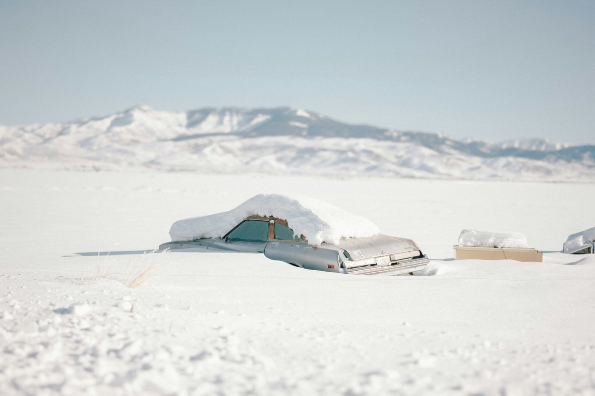classyhunting's tweet photo. Abandoned #vintage car buried under deep snow in a vast winter landscape, with #distant #snow-#covered mountains under a clear #blue #sky. #Minimalist frozen #scene capturing #isolation and the harsh #beauty of #winter. https://t.co/VPNlvKbC3u