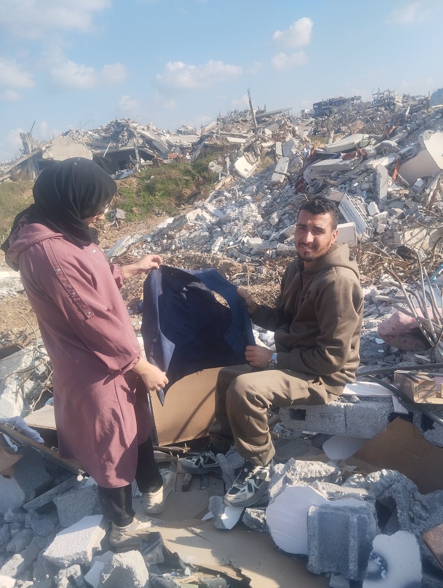 This is a photo of me with my wife, Yara, standing atop the rubble of what was once our home.
While searching through the debris, we found my wedding suit—buried beneath the ruins.

In that moment, we held it tightly and renewed the same promise we made on our wedding day:
to