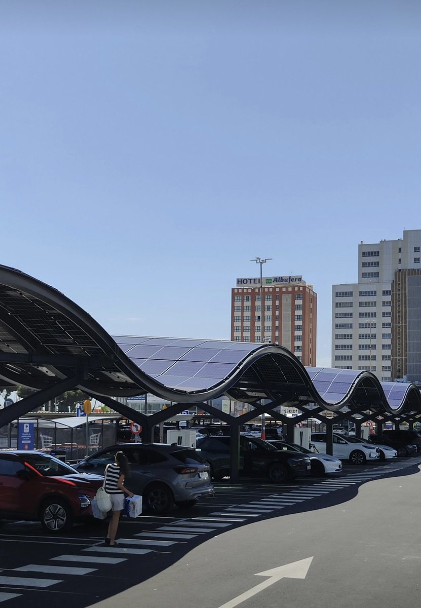 Pérgola solar curva con módulos bifaciales que recargan vehículos eléctricos y dan sombra, optimizando espacios y energía limpia en España. 
#CleanEnergy #Sustainability