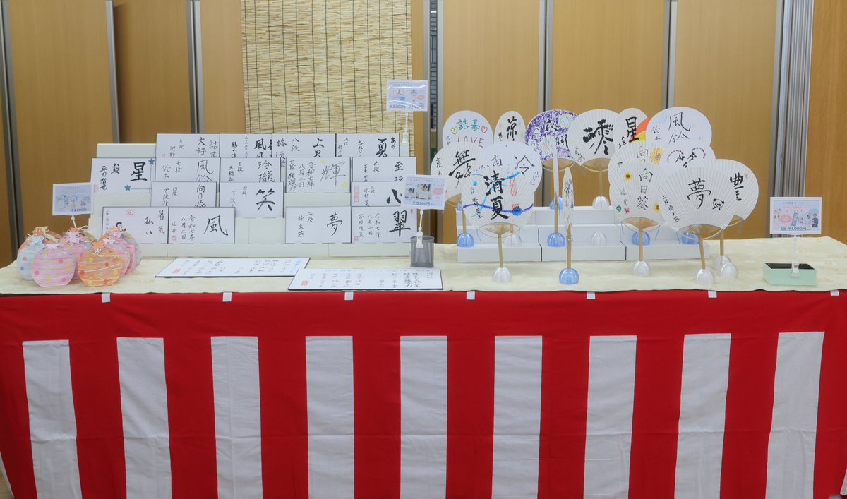 YukataIGO's tweet photo. 浴衣囲碁まつり恒例の物販ブースもステージ横で常設されました✨🪭
夏らしいグッズが盛りだくさん！近くには手の空いている棋士たちの姿も見えます。

沢山のグッズがご来場の皆様のお手に渡りました！在庫のある商品は、８月中に事後物販として販売予定です✨是非お楽しみに！
#浴衣囲碁まつり2025 https://t.co/4hafjf9NWq