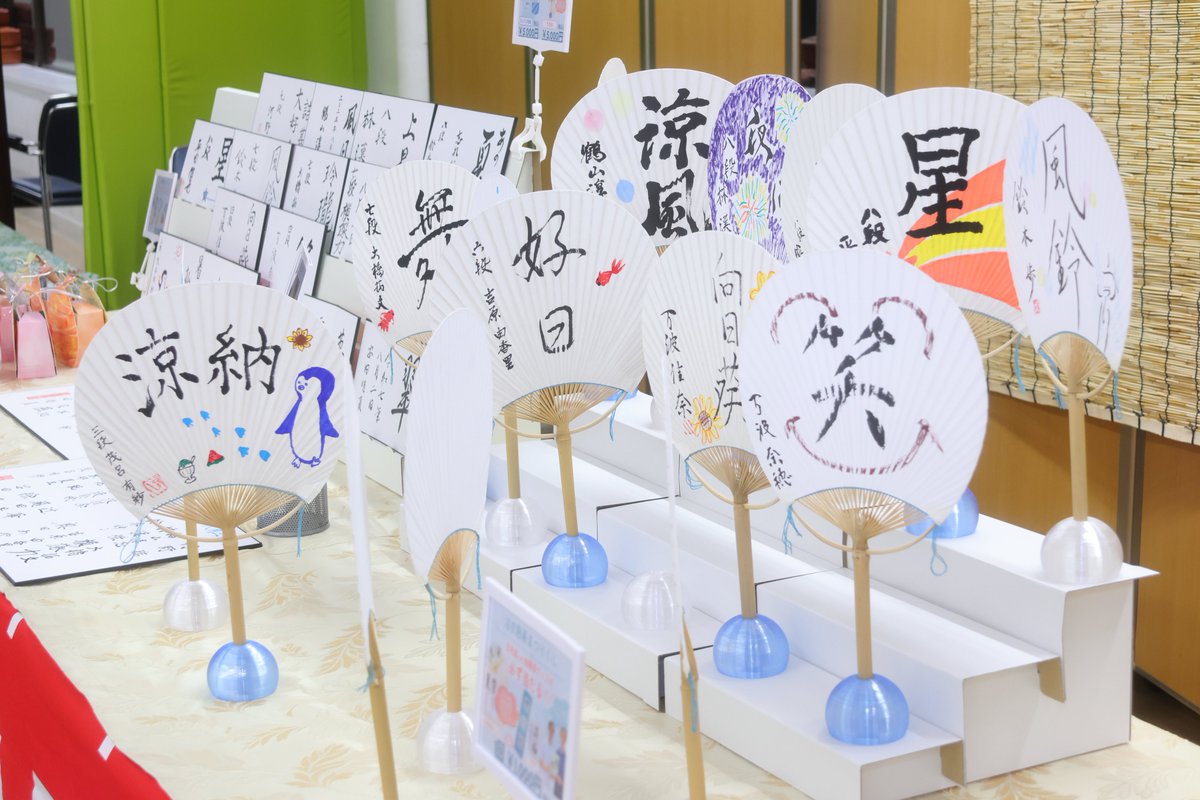 YukataIGO's tweet photo. 浴衣囲碁まつり恒例の物販ブースもステージ横で常設されました✨🪭
夏らしいグッズが盛りだくさん！近くには手の空いている棋士たちの姿も見えます。

沢山のグッズがご来場の皆様のお手に渡りました！在庫のある商品は、８月中に事後物販として販売予定です✨是非お楽しみに！
#浴衣囲碁まつり2025 https://t.co/4hafjf9NWq