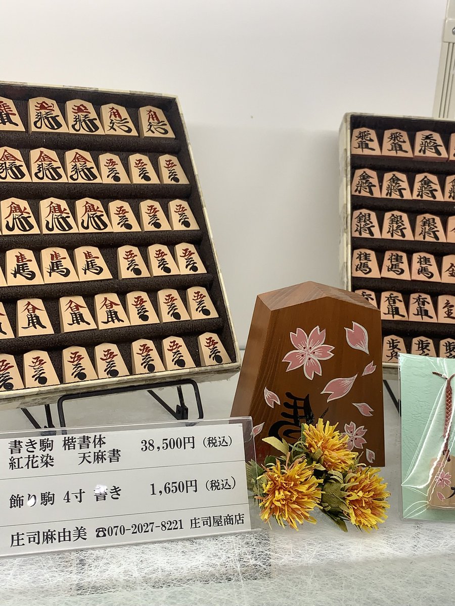 【伝活】山形県天童市といえば、将棋の駒。「道の駅 天童温泉」では駒の展示に加え、女性の職人さんによる彫り駒の実演が行われていました。展示で目を引いたのは、紅をあしらった書き駒。黒漆とのコントラストが魅力的でした。女性の書き師さんの作品です