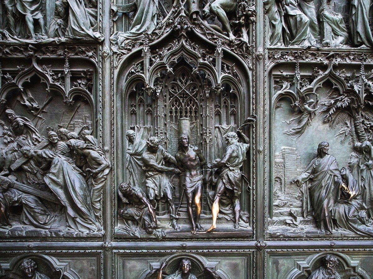 Kapılar sadece geçmek içindir; ama bu panellerin önünde geçmek değil, bakakalmak isteyebilirsiniz.

Bu kapılarda bronz, sanki eriyip duygulara dönüşmüş.

Lodovico Pogliaghi’nin 1906’da tamamladığı kapıların ayrıntılarındaki incelik, onu sıradan bir kapı olmaktan çıkarıyor.