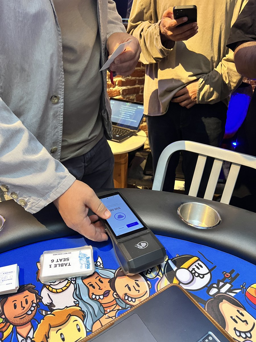 在 OnChainSF 活动期间，一位人士在以表情包为主题的扑克桌上使用 Base Pay 的轻触支付终端