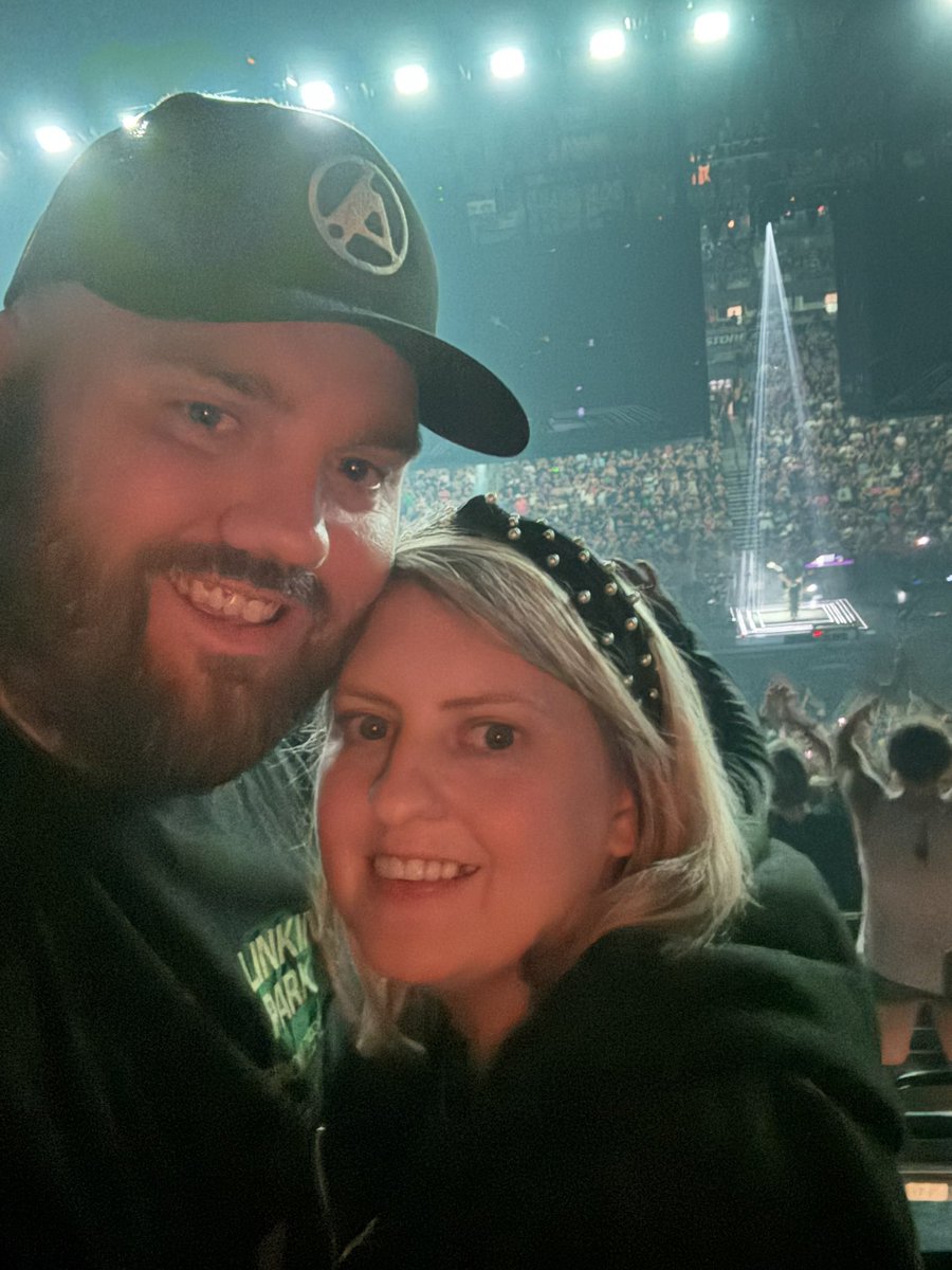 dhall_73's tweet photo. Linkin Park Live Review – Time Heals, Music Endures

For me, last night was a dream realized. I’ve always wanted to see Linkin Park live, but when Chester passed, I thought that dream was gone forever. Like so many fans, I couldn’t imagine how the band could go on. Then Emily came… not as a replacement (because Chester can never be replaced), but as someone who brought her own power, grit, and humanity.

When From Zero first released, I’ll admit I questioned the validity of the band continuing without Chester. At times it was hard not to feel like an imposter was behind the mic. But time heals, and I’ve grown to truly enjoy listening to From Zero. The band is leaning into Emily’s strengths and ability to move from polished vocals to raw screams. This created and creates music that both maintains and builds on Linkin Park’s authentic tone. Songs like Two Face felt like a continuation of Hybrid Theory, not an imitation.

Last night confirmed that for me. From start to finish, there was no sense of an outsider on stage. Emily doesn’t replace Chester… she belongs in Linkin Park! One of the most powerful moments was when she leaned over the rail separating fans from the stage, making herself visibly vulnerable, and showing the human connection that has always been the heartbeat of the band.

Lindsay Hall, who came mostly to support my love for the band, left captivated. She was blown away by Emily’s range, but also by the joy she saw on stage and in the crowd. Linkin Park clearly loves playing together, and their fans clearly love them right back.

The energy was unreal. A mosh pit and crowd surfing lasted for hours! This is something I’ve rarely seen feel that genuine and alive. And just to add to the surreal fun, I had the weird honor of standing next to a banana man holding a sign that read “Directed by Michael Bay.” It sparked laughs, and it helped Lindsay and others recall the Transformers connection to What I’ve Done, now trending again online.

And while last night was unforgettable, I also want to say this: Linkin Park has always spoken to adult thoughts and emotions such as loss, anger, resilience, and healing. That’s part of what makes their music so powerful, but it also means the themes and language aren’t really suited for young kids. Their shows are raw, honest, and human which is exactly why they connect so deeply with the people who need it.

Verdict: Chester can never be replaced. But Emily has proven she cannot be either. Linkin Park has found a new normal that is rooted in respect, joy, intensity, and connection. Last night wasn’t just a concert; it was living proof that Linkin Park is still authentically Linkin Park.
#fromzeroworldtour #LinkinParkNashville #LinkinPark