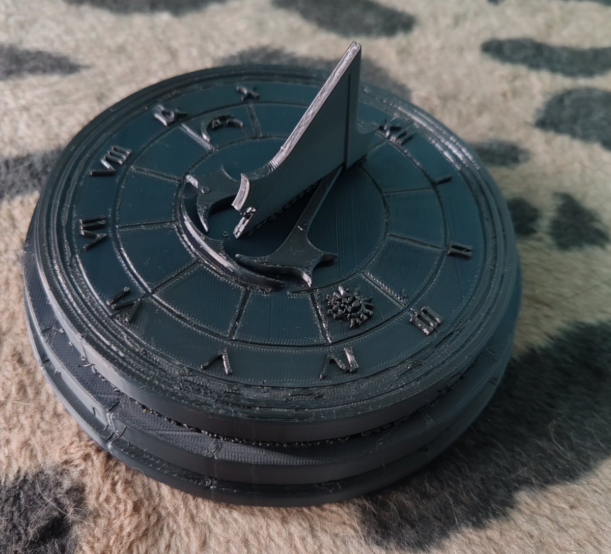 Custom AC Sundial, Adorned with symbol taking the form of the gnomon

Does it work? Yes.

I've shined a torch and also put it out, when faced correctly to north, it'll show the correct time properly in the sun using the shadows as a indicator

While the moon and sun didn't come