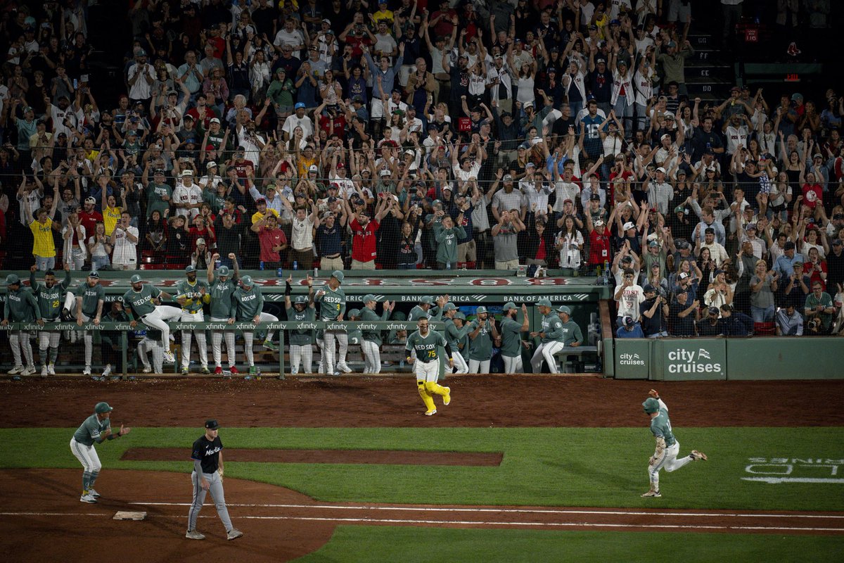 Wide shot of the crowd at Fenway Park cheering as Trevor Story runs toward first base after hit walk-off hit for the win against the Marlins. The Red Sox dugout is seen cheering while Carlos Narváez runs to meet Story. The team is seen in their Fenway Greens City Connect uniforms.