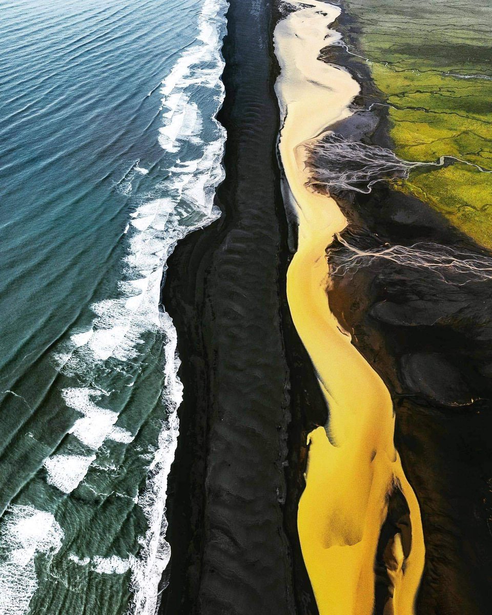 9. Holtsós is a magical place in Iceland where a green field, a yellow river, a black beach, and the ocean meet.