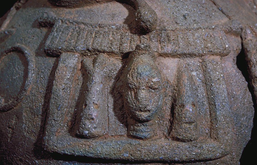 Images on another side of same ìṣà, ca1200:

Snake with its head hanging down from the roof of a stylized edifice (royal court, temple). 

The interior shows a naturalistic central head (?ọba) flanked by stylized ones (?ẹ̀ṣọ́).
——

Compare with later pre-colonial Bini palace