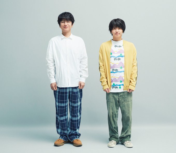 この画像には、無地のグレーの背景に並んで立っている 2 人の男性が、プロモーション写真のためにさりげなくポーズをとっている様子が描かれています。左の男性、及川光弘は、白いボタンアップシャツと青いチェック柄のズボンに茶色の靴を履いており、今後のドラマで心優しいゲイのキャラクターを演じています。右の手越裕也は、山と波の柄が描かれたカラフルなTシャツの上に黄色のカーディガンを着て、緑のズボン、白いスニーカーを履き、7年ぶりに黒髪の新着でクールなゲイの中学校教師を演じている。投稿テキストでは、10月に開始予定の日曜新ドラマ「ぼくたちん家」(ぼくたちん家)での彼らの役柄が明らかになり、彼らの夢のコラボレーションとユウヤの劇的なテレビ復帰を記念している。プラットフォームの透かしは表示されません。