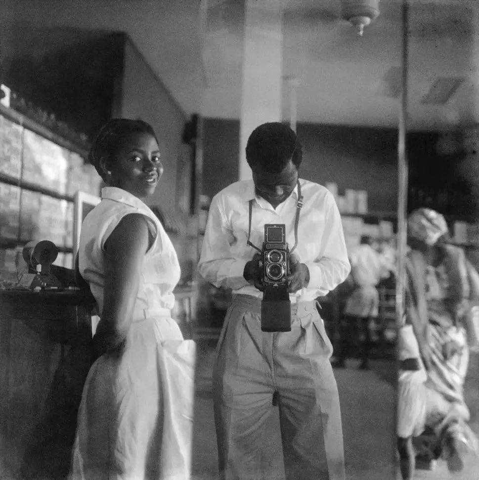 james barnor taking a self-portrait 
with a store assistant. accra, ghana. (1952)