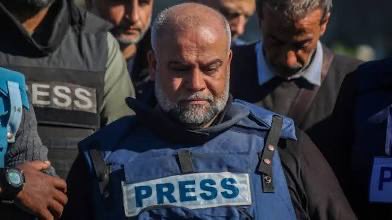 Wael Al Dahdouh wearing a blue press vest with "PRESS" text. Hussam Abu Safiya in a dark blue medical scrub top with a stethoscope around his neck.