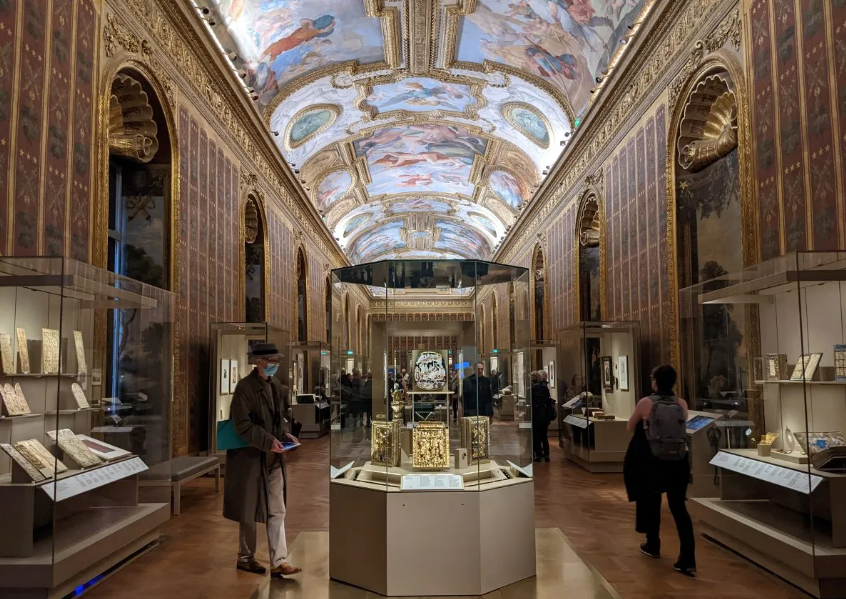 ชั้น 1 : ทางเข้า – เรือนกระจกแห่งห้วงเวลา

ผู้มาเยือนเริ่มต้นการเดินทาง ณ ประตูหินโบราณที่สลักด้วยอักษรลี้ลับ เปล่งประกายเรืองรองราวกับมีชีวิต 

เรือนกระจกรอบด้านปกคลุมด้วยไม้เลื้อยสายพันธุ์ประหลาดและพืชกินแร่ แสงแดดส่องลอดกระจกสะท้อนแสงสีมรกตสู่พื้นหิน