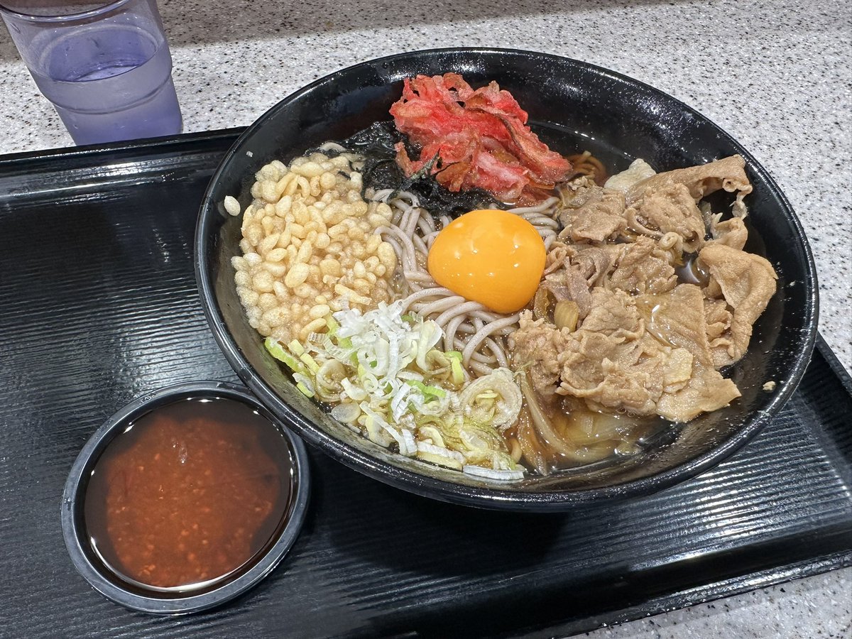 富士そばで鳥羽シェフ監修の月見うま肉そば。今度は温ね。
玉ねぎと共に煮込んだ豚肉、卵黄、ねぎと海苔までは冷と同じ。そこに揚げ玉と紅生姜のカットが追加。ネギの切り方も変えてるね。別皿はコチュジャンではなくラー油。