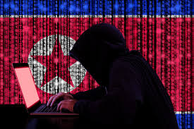 Hooded hacker typing on laptop with North Korean flag digital background