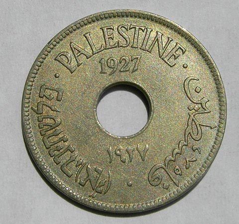 A coin with a central hole, inscribed with "PALESTINE 1927" at the top in English, and Arabic script around the edges. Additional text in Arabic and Roman numerals "IV" is visible below the hole.