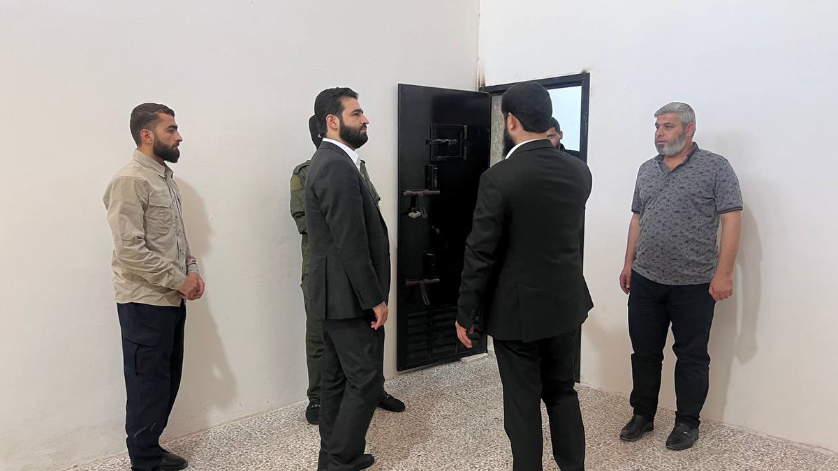 QUSAY_NOOR_'s tweet image. In the photo, the Minister of Interior in #Idlib appears before a giant screen displaying, through cameras, images of prison wards holding both civilians and #criminals facing personal and public charges. 

The image reflects a qualitative shift in monitoring the behavior of