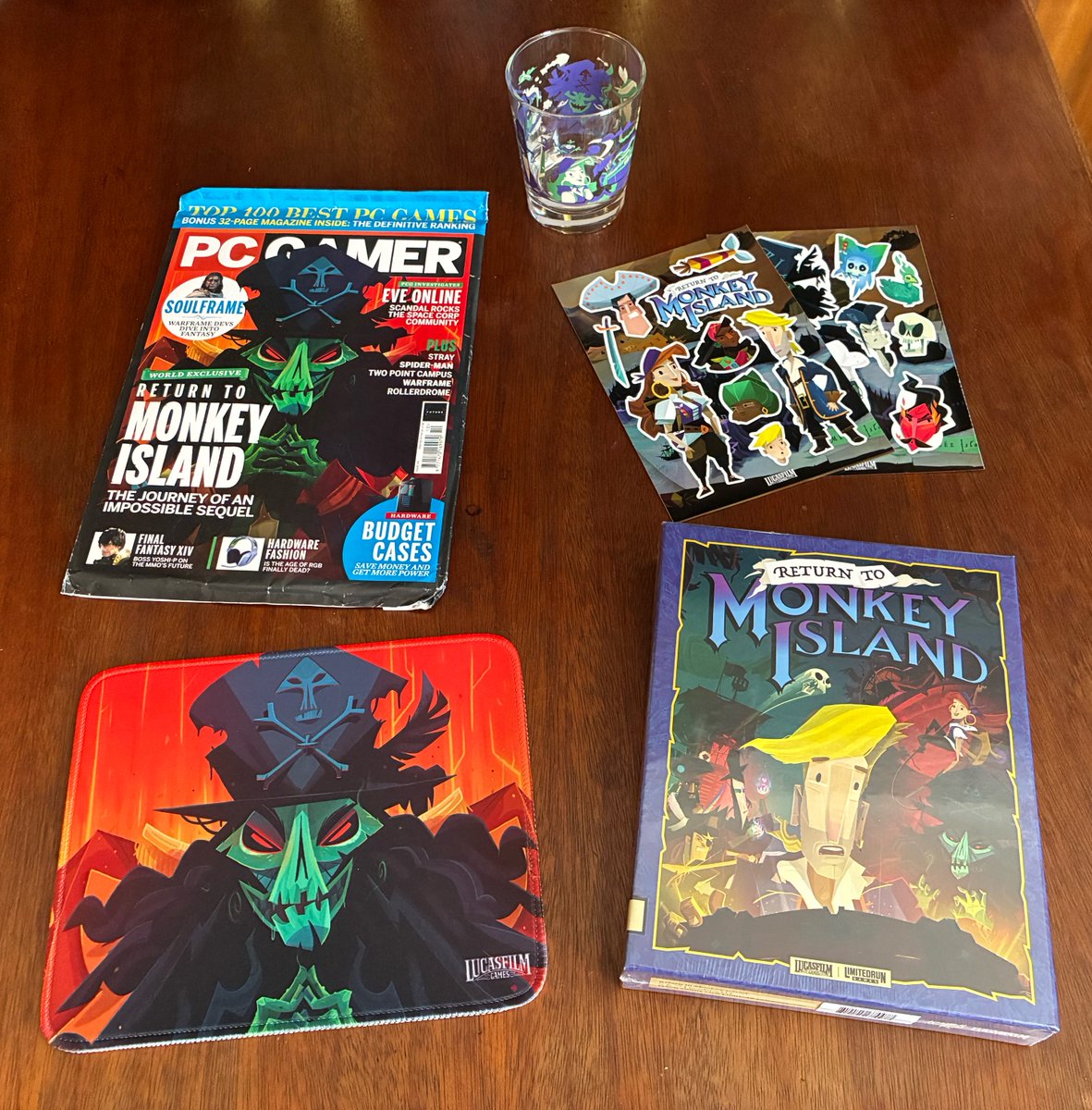 Return to Monkey Island memorabilia: PC Gamer with LeChuck on the cover, glass, stickers, a mouse mat, and the big box.