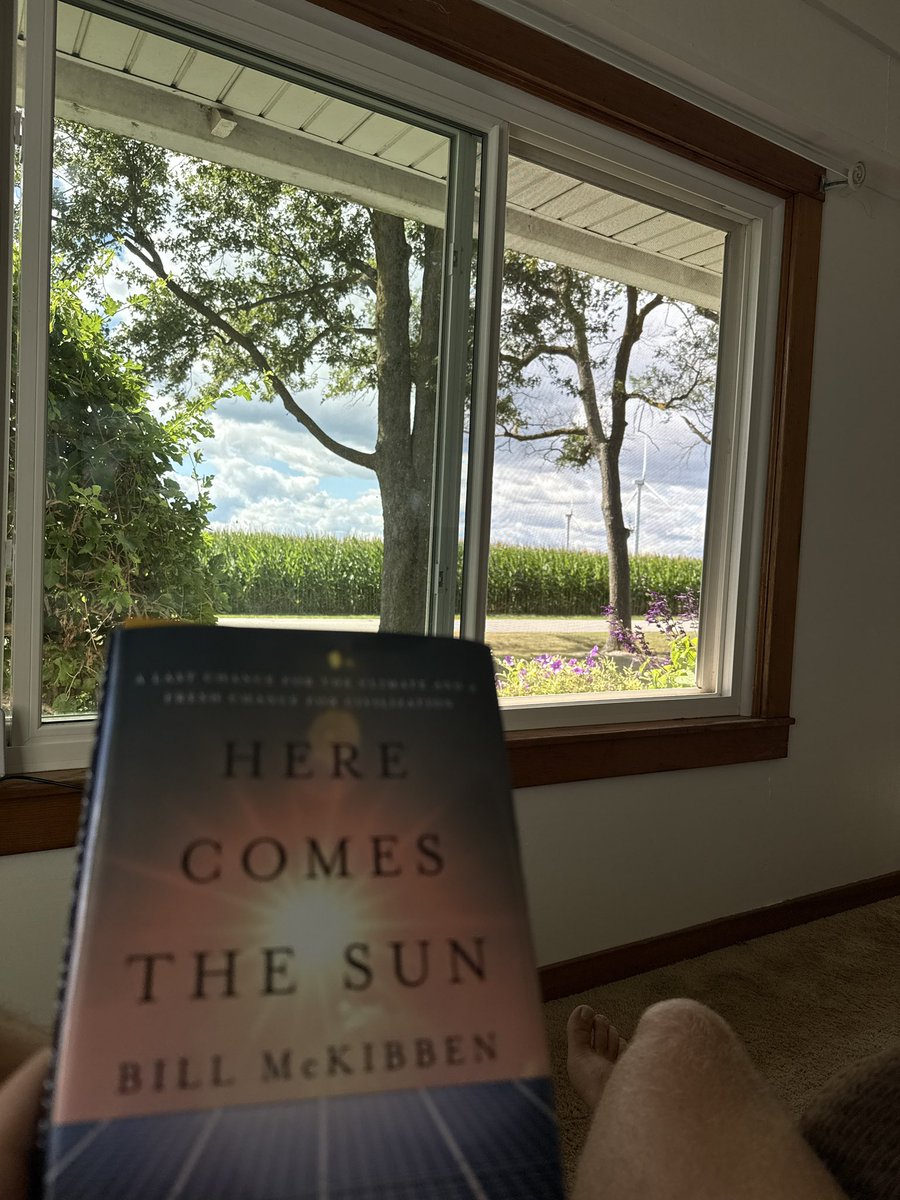 Enjoying a relaxing Sunday read under a bright, sunny sky, with wind turbines spinning gracefully in the distance. Loving the book so far, <a href="/billmckibben/">Bill McKibben</a>!