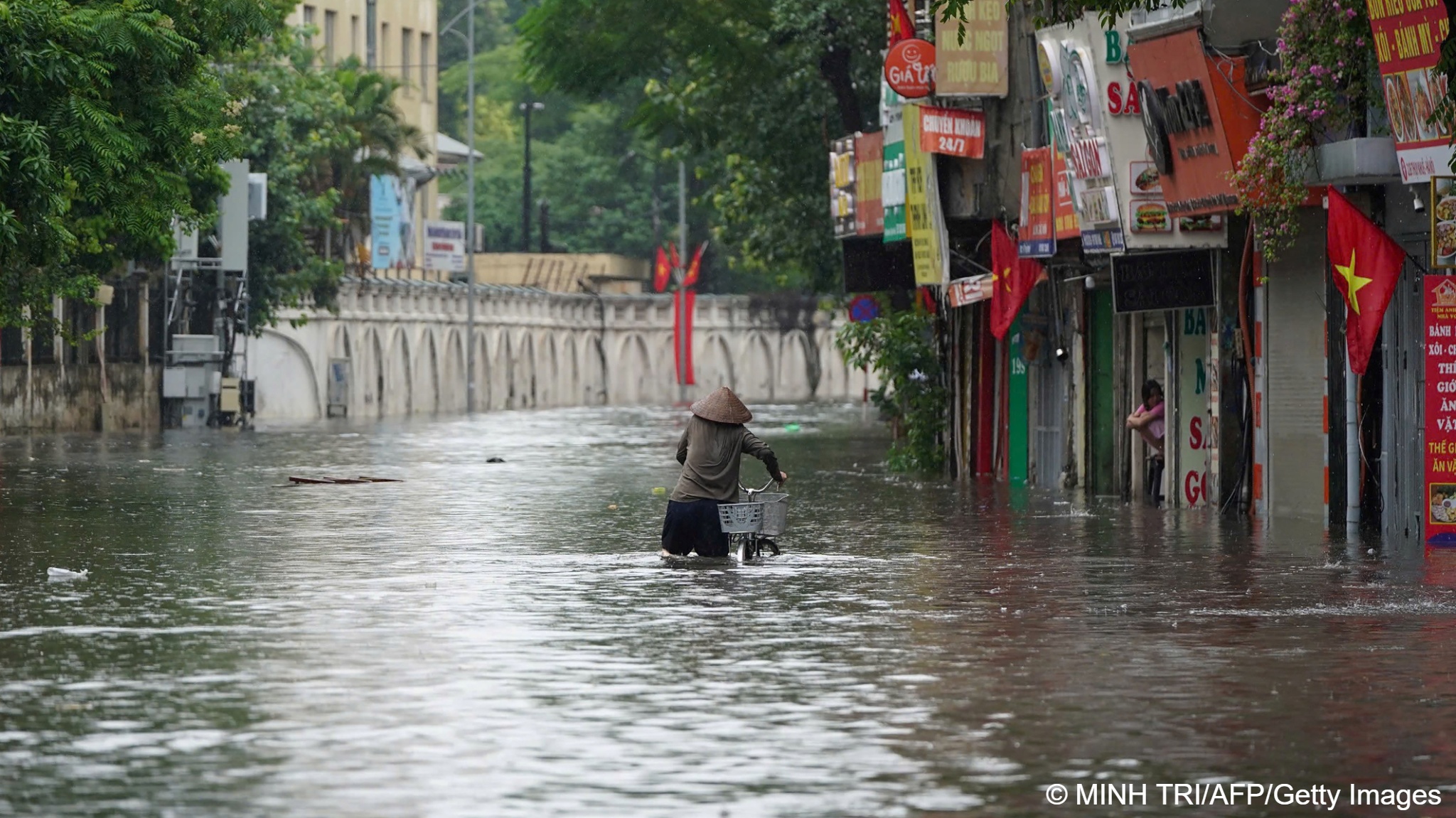 un hombre empujando un carrito en una calle inundada