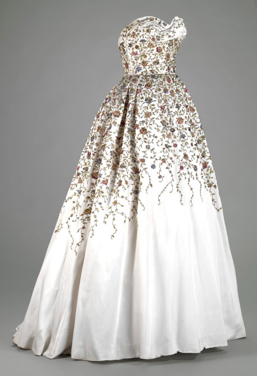 A closer examination of the strapless bodice of Balmain’s 1953 ballgown creates the impression of a decorative ceramic, moulded in white with a fruit of floral embellishments trailing towards the hem <a href="/NewfieldsToday/">Newfields</a> #fashionhistory