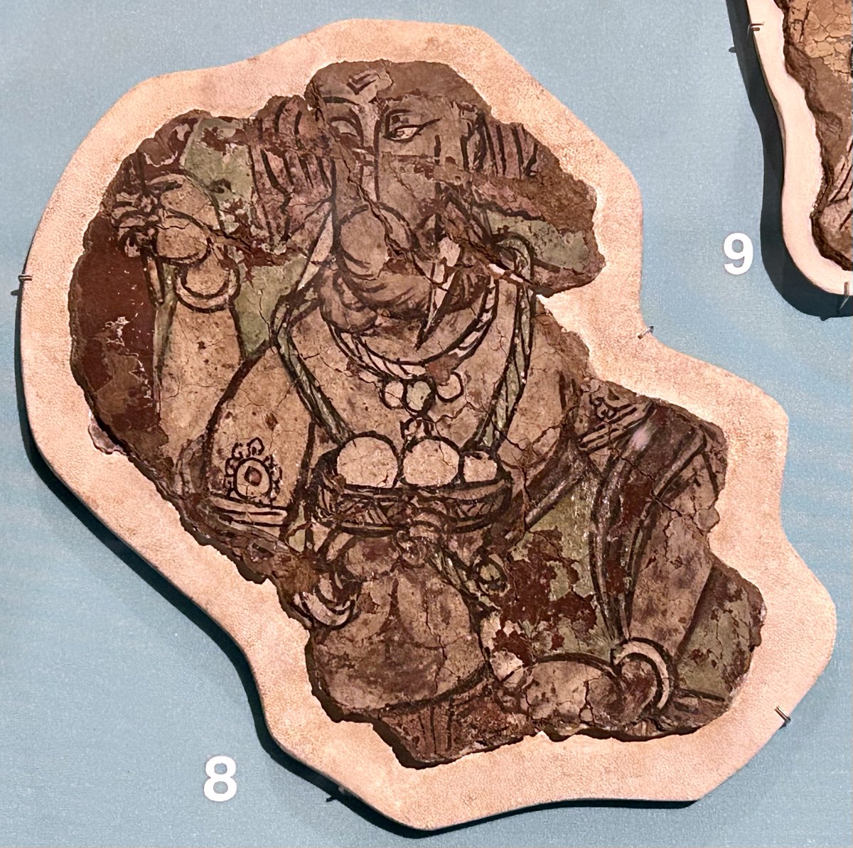 Painted votive panel with Gaṇeśa, 600-800 CE, Endere, Xinjiang, China and a fragment of a wall painting depicting Gaṇeśa, 500-600 CE, Khadalik, Xinjiang, China. Both are on display in the Beyond India section of the British Museum's ongoing Ancient India exhibition.