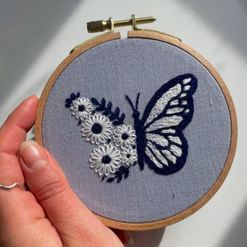 Delicate embroidery, a butterfly's grace, framed in soft lavender.  A symphony of stitches, a floral embrace.🦋 #embroideryart