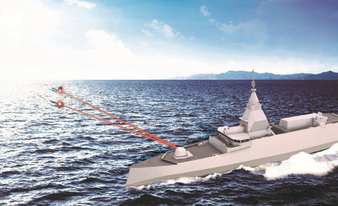 A naval ship on the ocean with red laser beams extending from its deck toward two small objects in the distance. The ship has a sleek, modern design with a prominent radar mast. The ocean is depicted with waves under a clear sky with distant mountains.