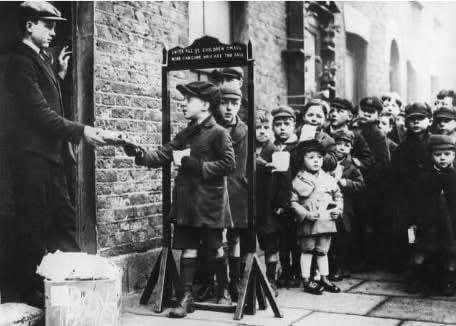 Discovery_CN's tweet photo. 1930年代，伦敦东区的孩子们排队等待慈善组织发放小礼品包。一个标语显示了孩子们可以进入的最大身高：“所有小孩子都可以进来，太高的孩子不能进入。” https://t.co/8slU0ool1f