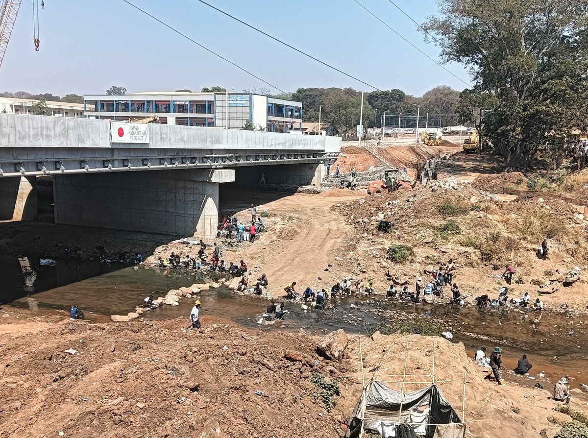 exitworker's tweet image. マラウイ首都のリロングウェ中心部では日本の援助で幹線道路の橋梁の架替え工事中。日の丸も掲げられてる。しかしこの旗の真ん前で「ヘイ、チャイナ！」と声をかけられてズッコケた。川では人々が洗濯している何とものどかな首都の昼下がり。#アフリカ  #マラウイ