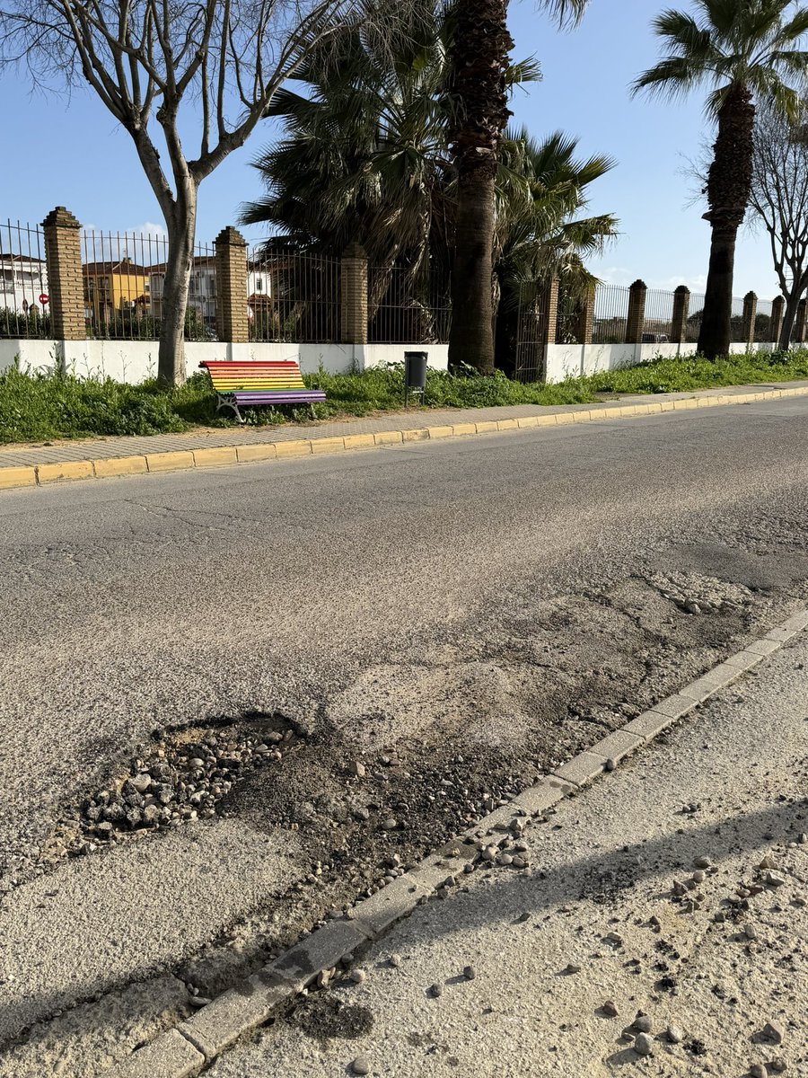 Este banco «inclusivo» de colorines representa todo lo que está mal hoy en día.

Pintarlo así no ha salvado ni una puta vida. Mientras, lo devora la maleza de un jardín sin mantenimiento y el asfalto por el que pasan miles de ciudadanos a diario se deshace entre socavones.