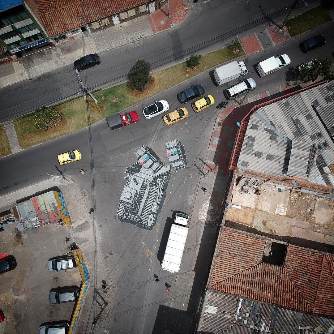 Aerial shots of a large-scale urban intervention: a mobile “stencil” — a tarp painted with a bulldozer and police cars — dropped into real traffic to create a temporary, cinematic street set. 
#mariuszwaras #mcity #dictadorartmasters #urbanart
<a href="/the_dictador/">pensamientosaldescubierto</a> @dictadorartmasters
