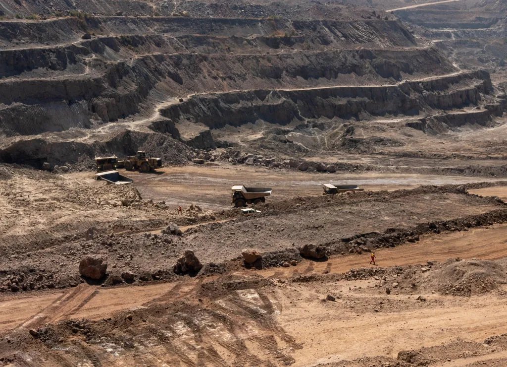 Aerial view of open-pit copper mine with trucks and workers